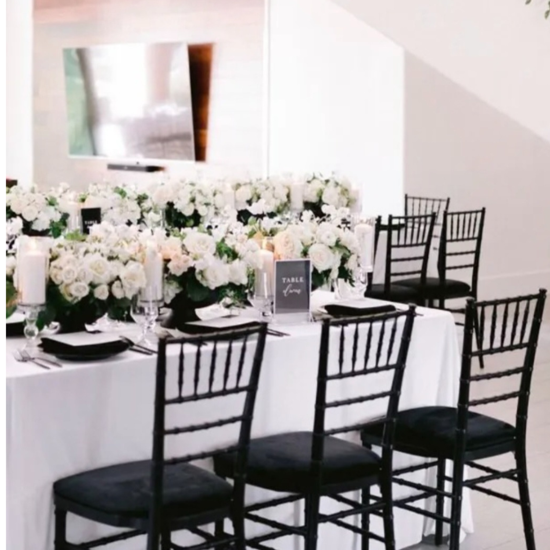 Sophisticated reception with black chiavari chairs and lush white floral table runner