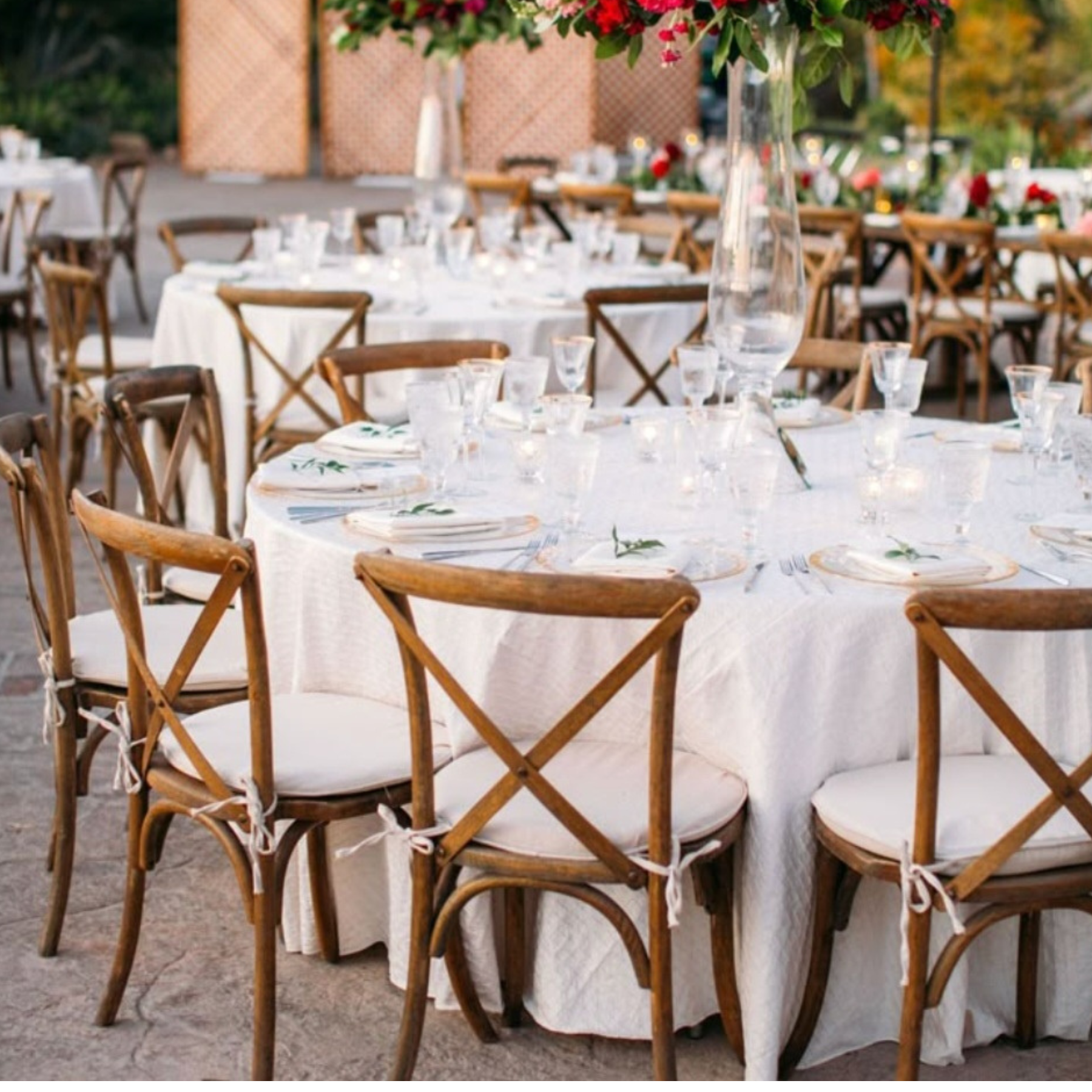 Elegant outdoor reception with crossback chairs, round tables, and floral centerpieces