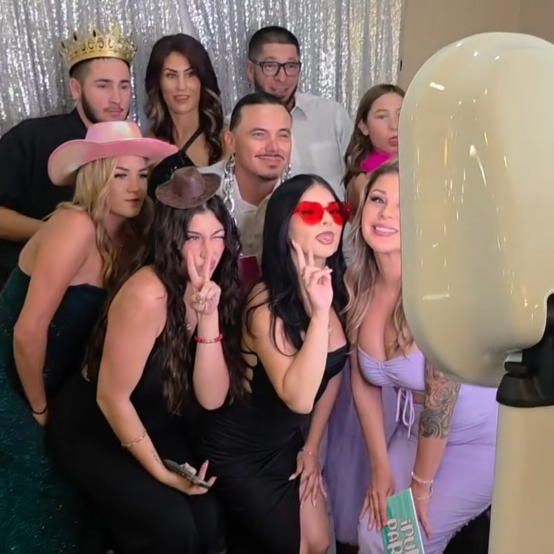 Group of guests posing at a photobooth with a sequin backdrop
