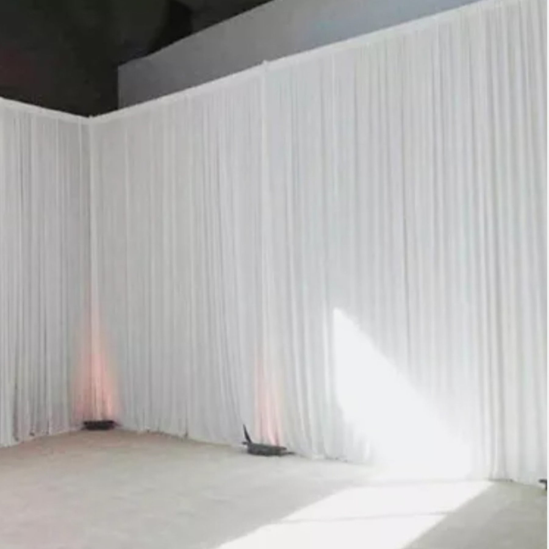 Large venue draped in white pipe and drape with uplighting