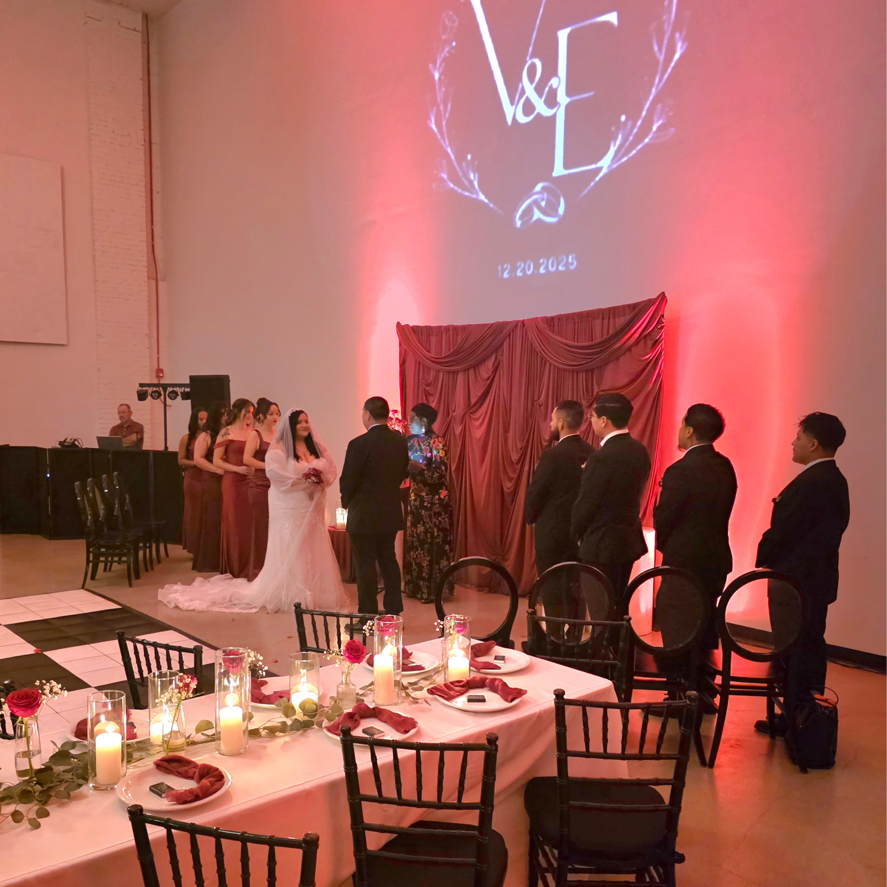 Wedding ceremony with red draped backdrop and candlelit sweetheart table