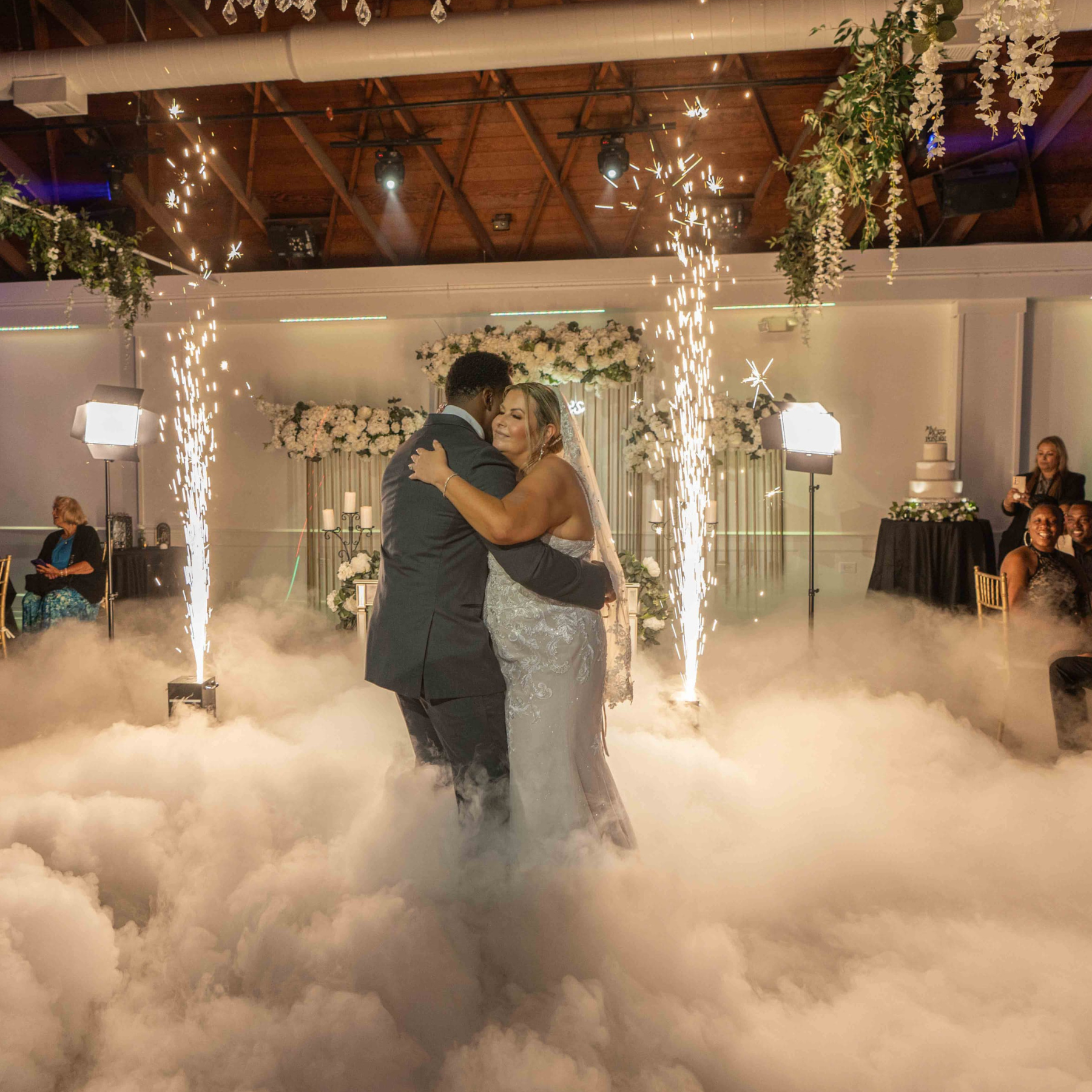 Wedding first dance surrounded by dry ice fog and cold sparklers with floral arch backdrop