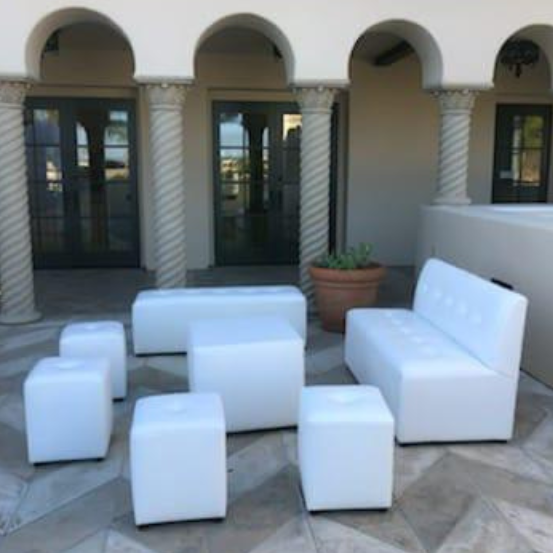 White modular lounge furniture set up in an elegant courtyard with arched architecture