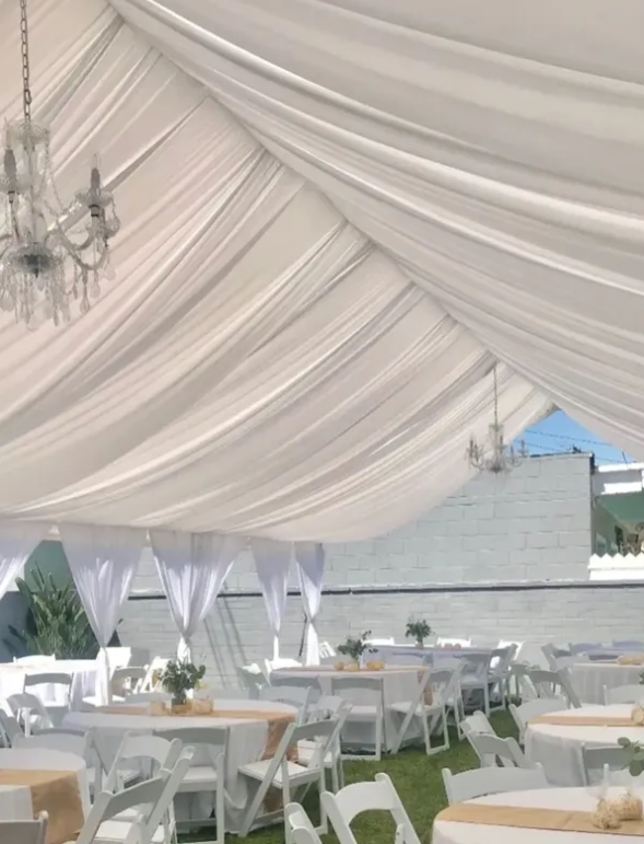 Draped canopy interior with chandeliers and black-clothed tables