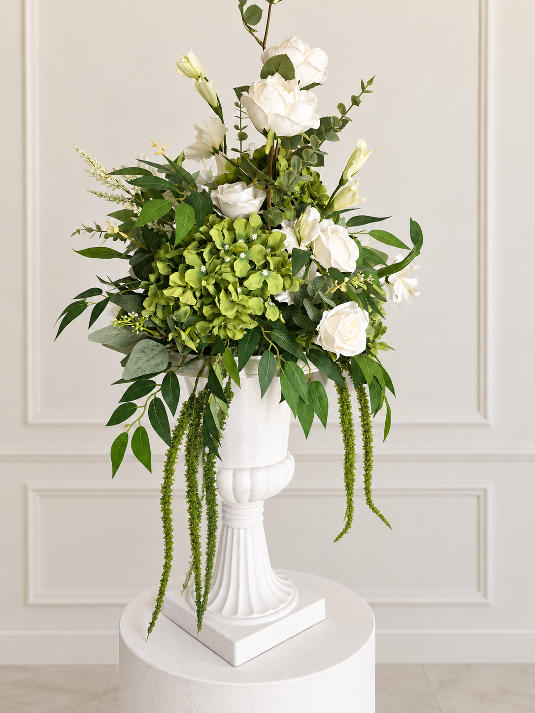 White roses and green hydrangea arrangement in white urn pedestal vase